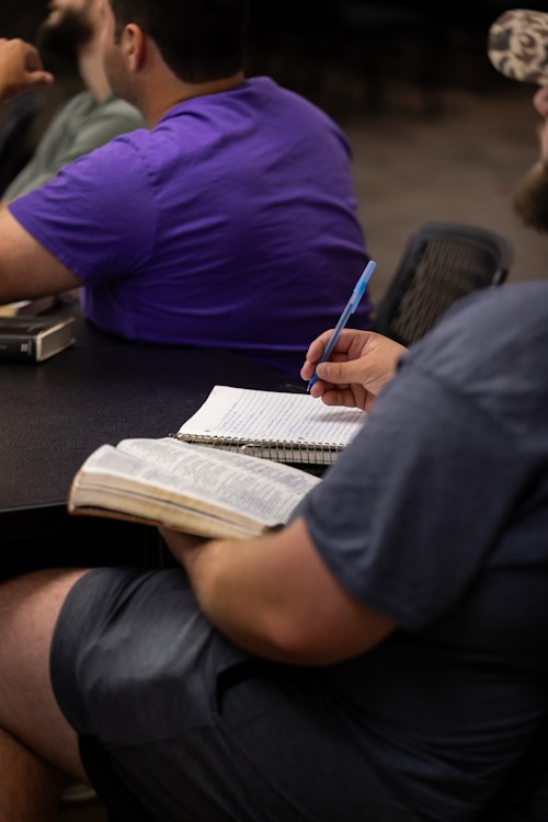 Man holding a Bible and taking notes, as in a Bible study